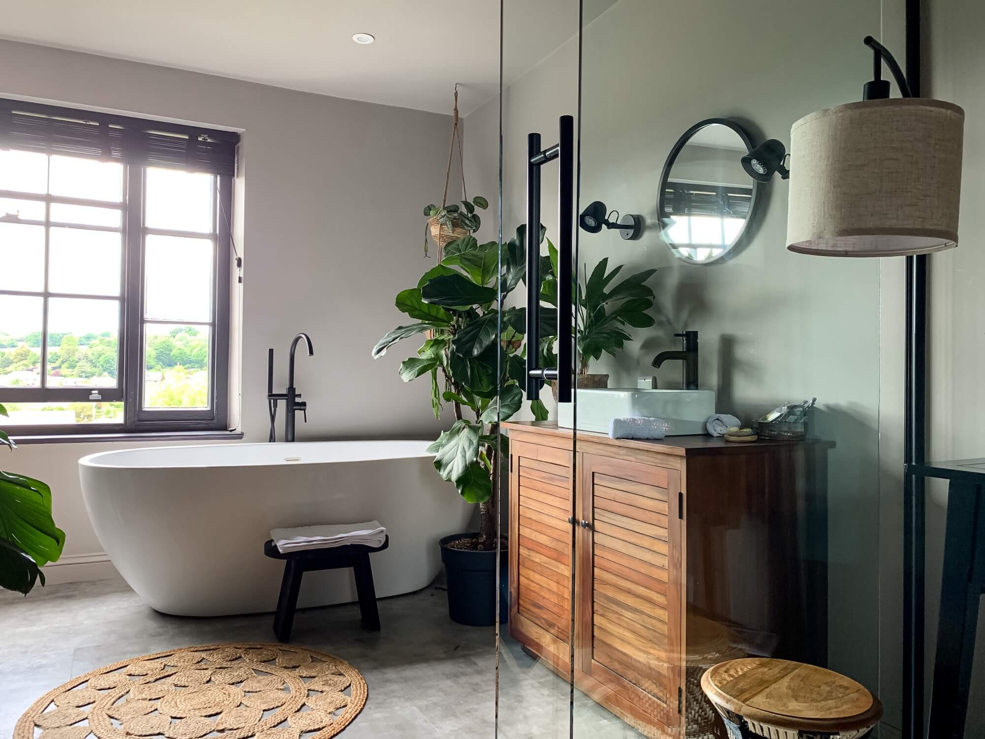 Modern bathroom with free-standing bathtub, black mixer and wooden commode - result of lavish bathroom renovation.